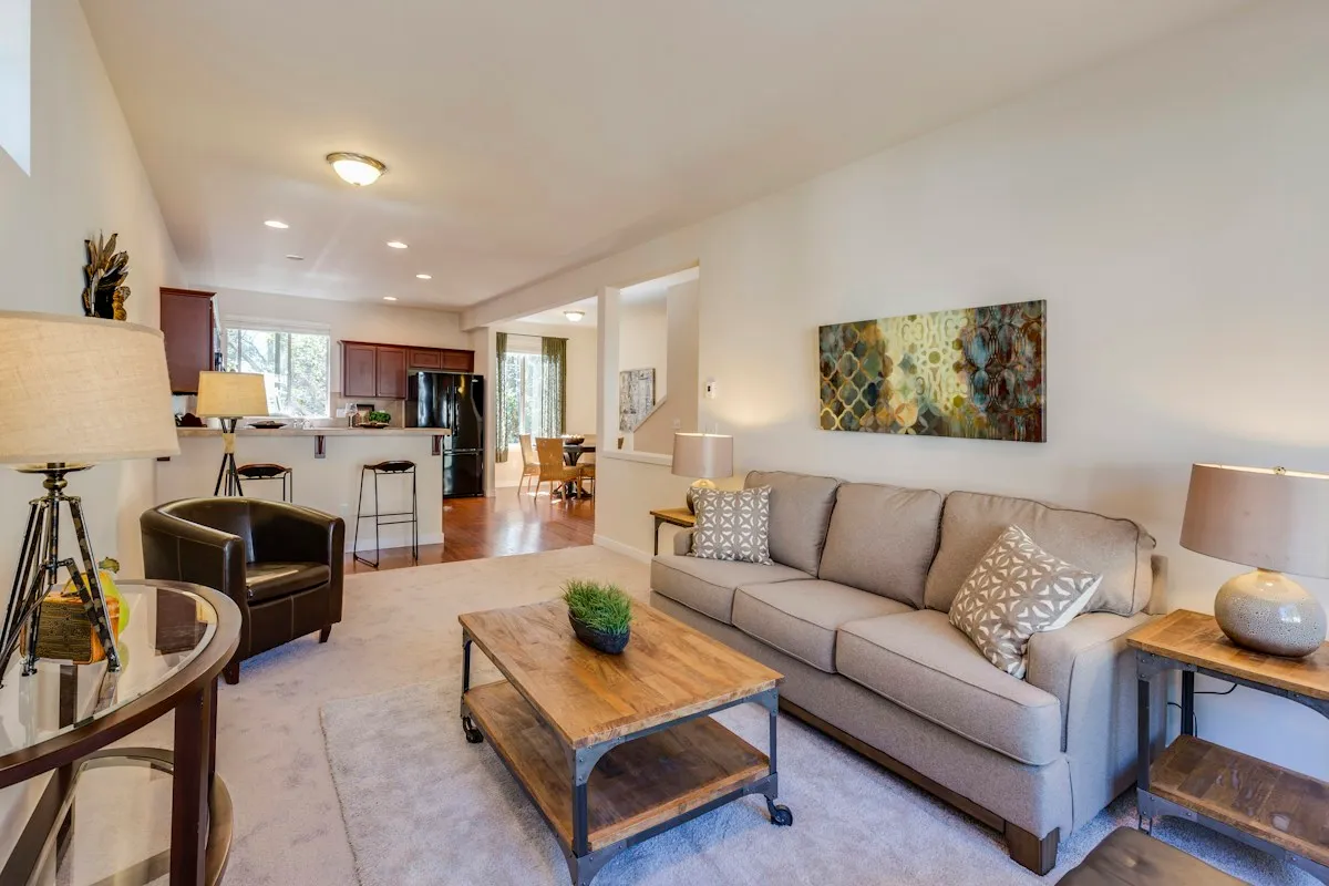 Neutral living room with a gray sofa, wood coffee table, and carefully placed cushions and lamps.